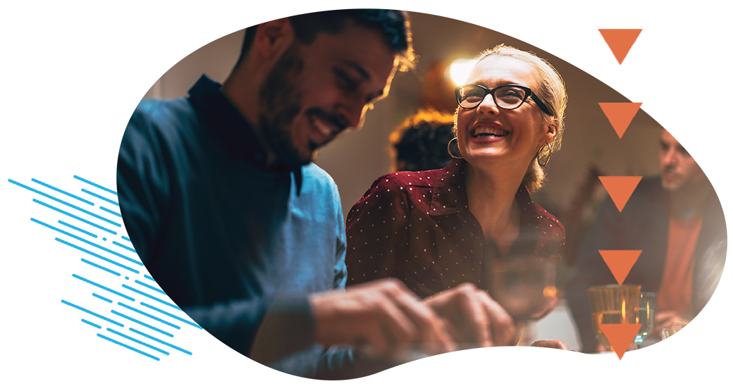 Happy friends talking and laughing together while sitting at dinner table and eating delicious food.